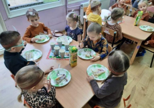 Dzieci z grupy 4-latków siedzą przy stoliku i jedzą tort.